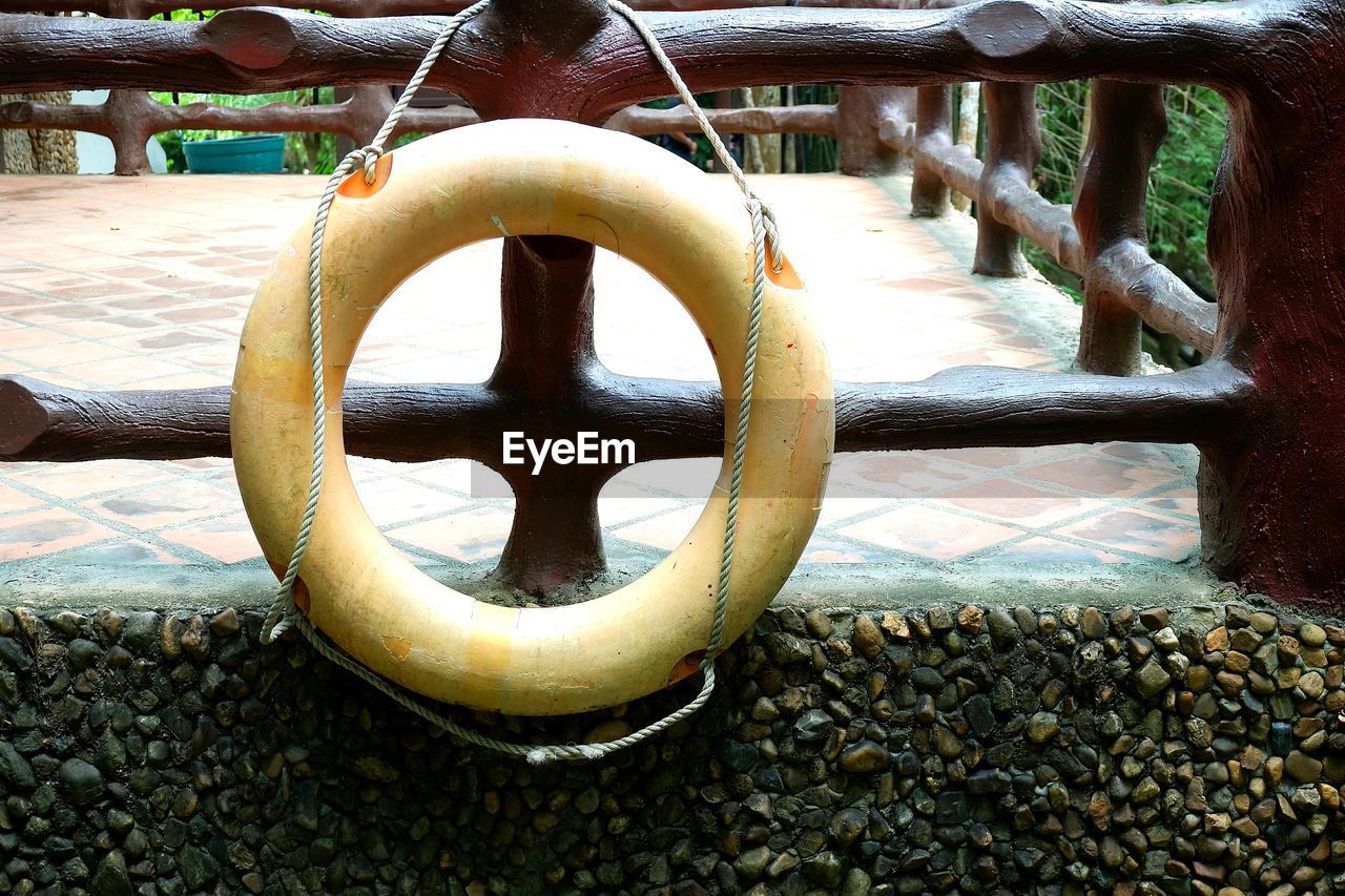 CLOSE-UP OF METALLIC RAILING BY WATER