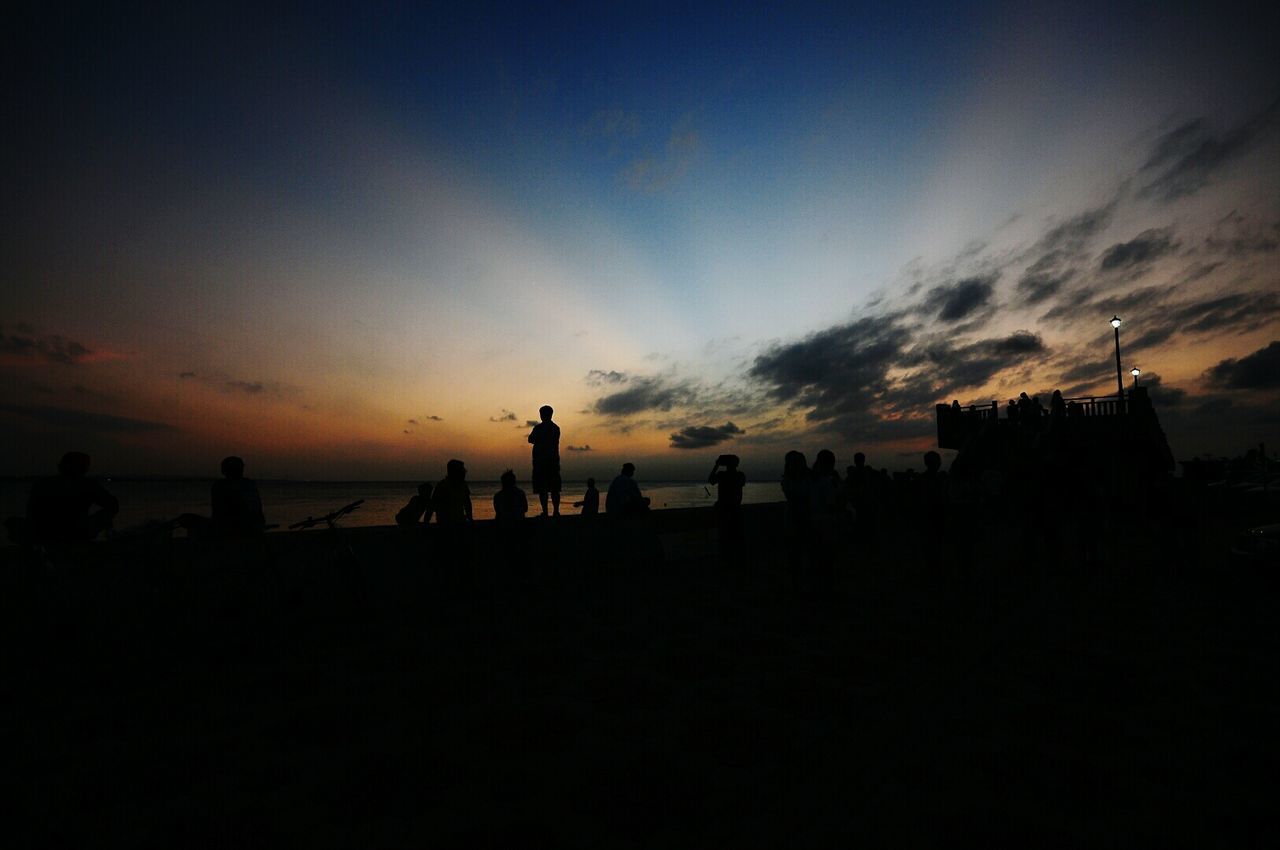 Silhouette people at beach against sky during sunset