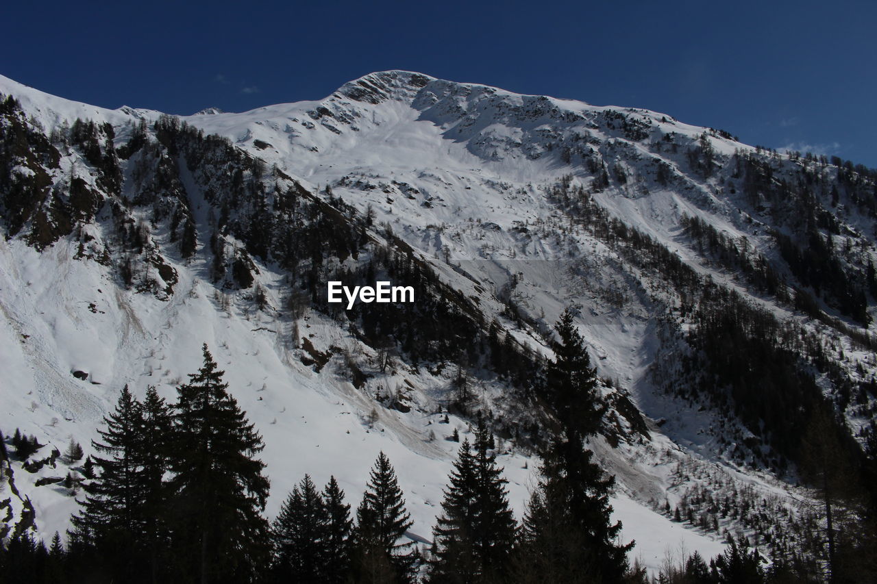 Scenic view of snow covered mountains against cloudy sky