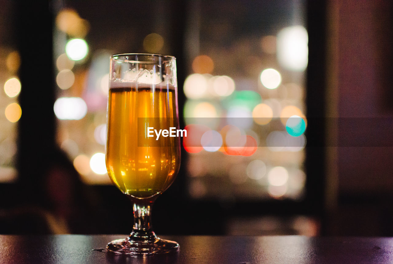 Close-up of beer in glass on table against window in bar