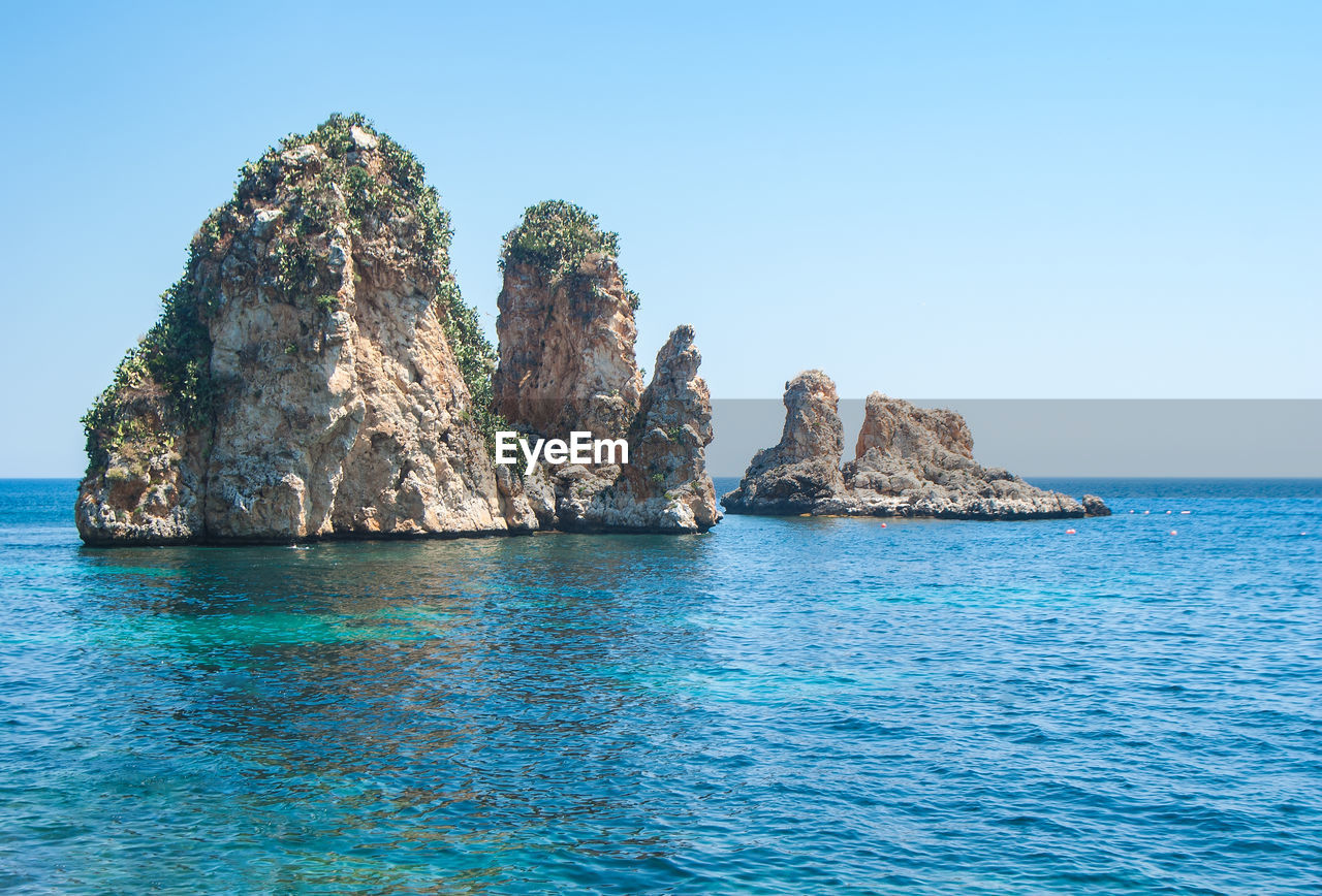 Scenic view of rocks in sea against clear sky