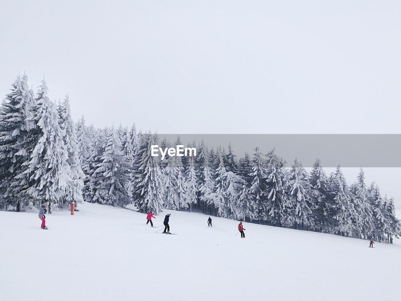 People on snow covered landscape against sky