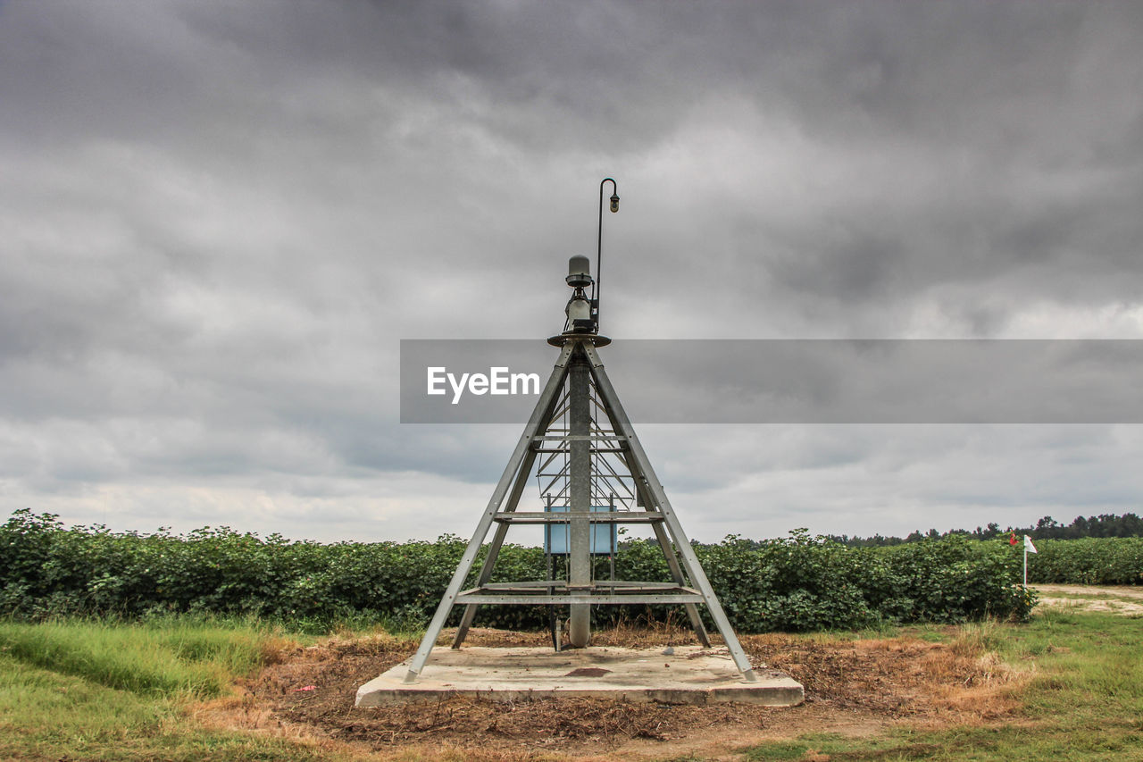 Traditional windmill on field against storm clouds