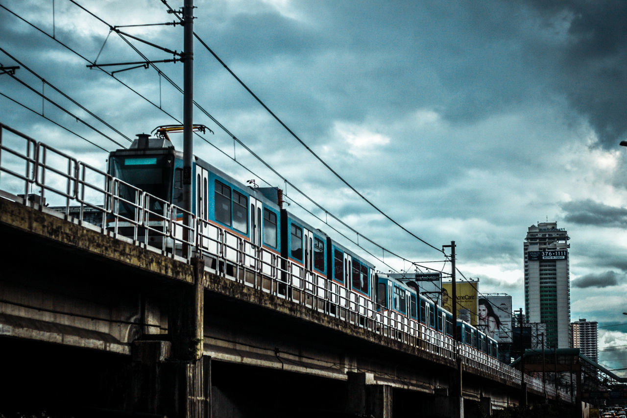 Low angle view of train on bridge against cloudy sky