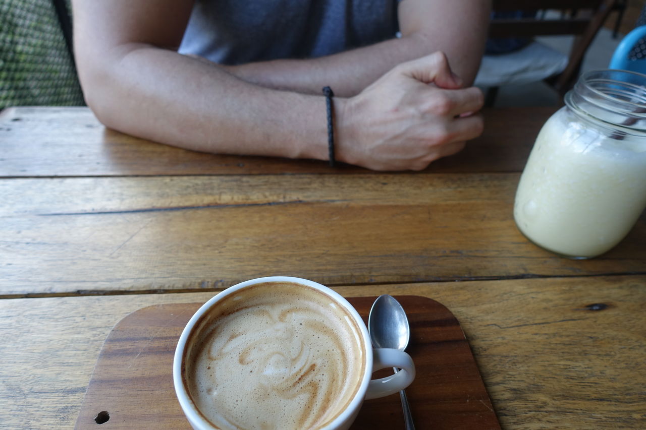 Midsection of man sitting at table with coffee cup