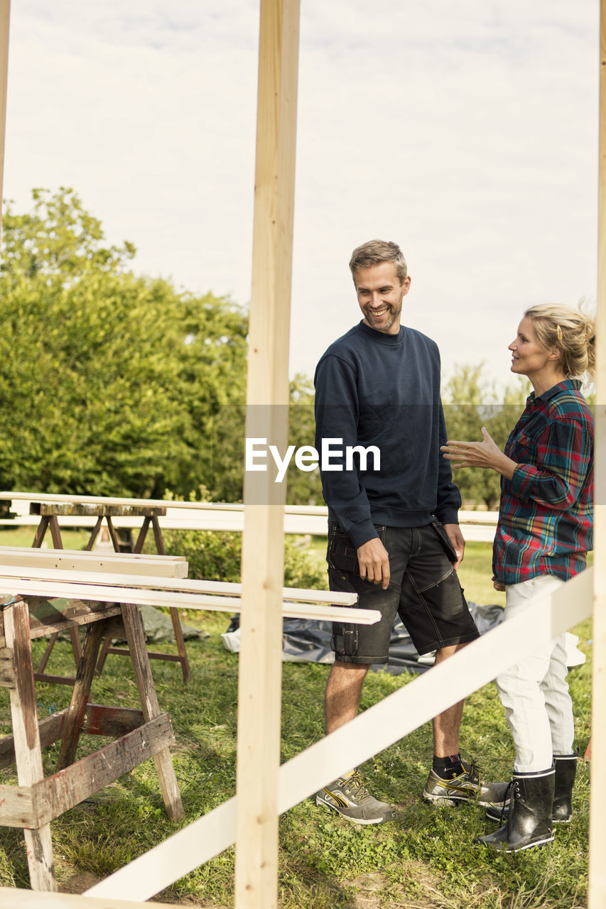 Happy couple discussing by wooden planks at farm