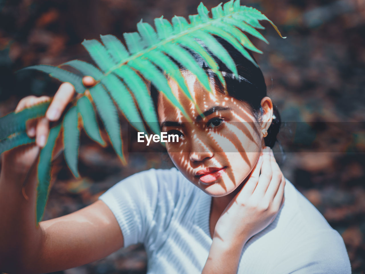 Close-up portrait of young woman holding plant standing outdoors