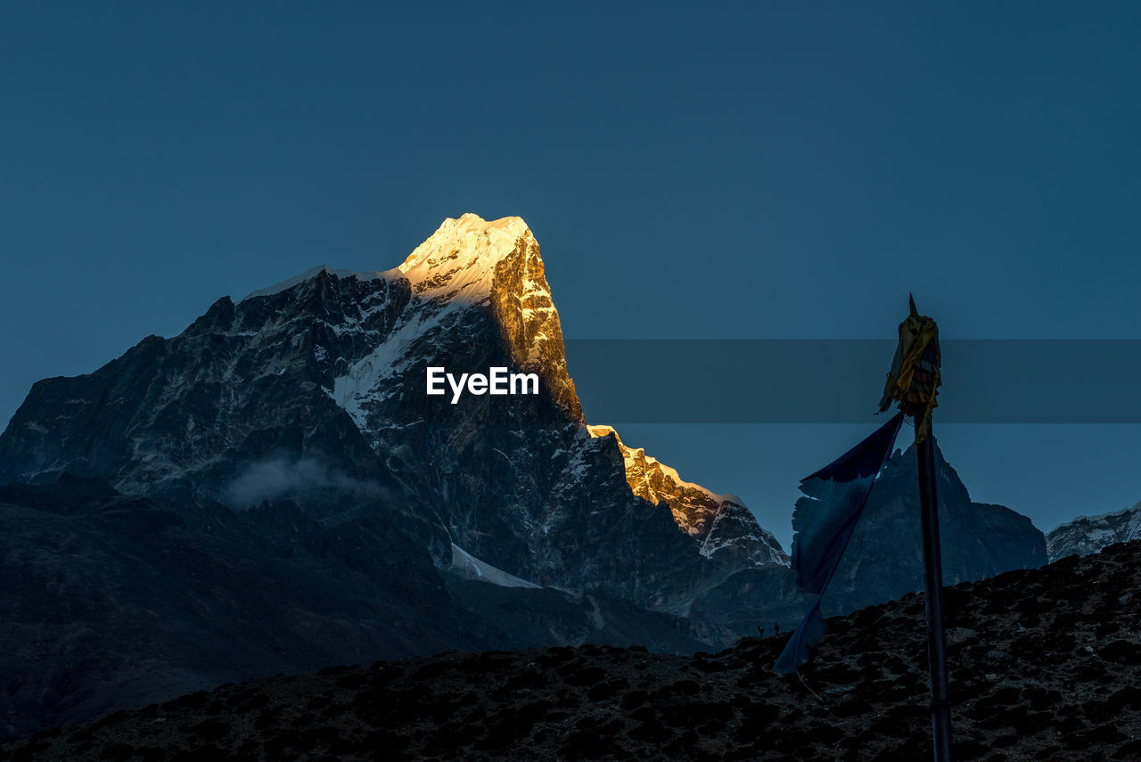 Low angle view of snowcapped mountain against blue sky