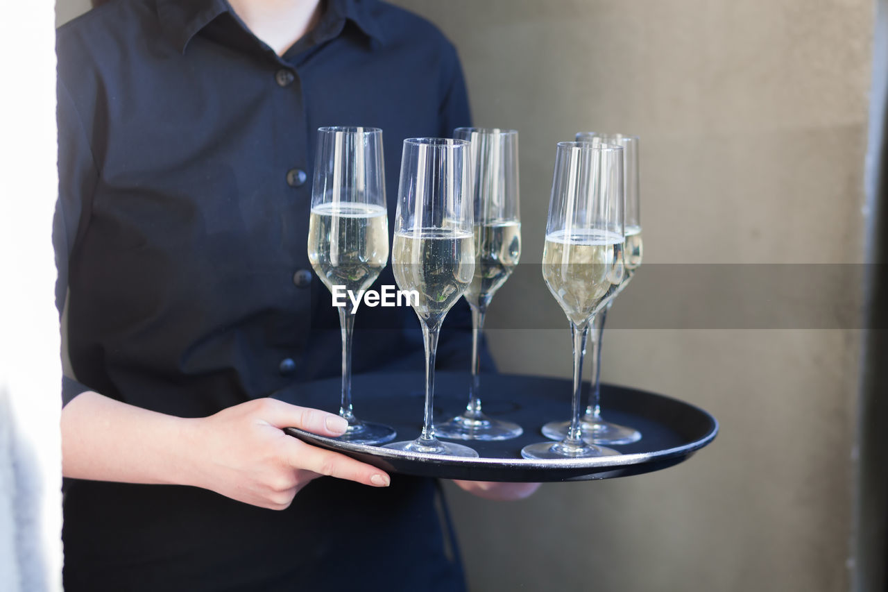 Midsection of waitress holding champagne flutes
