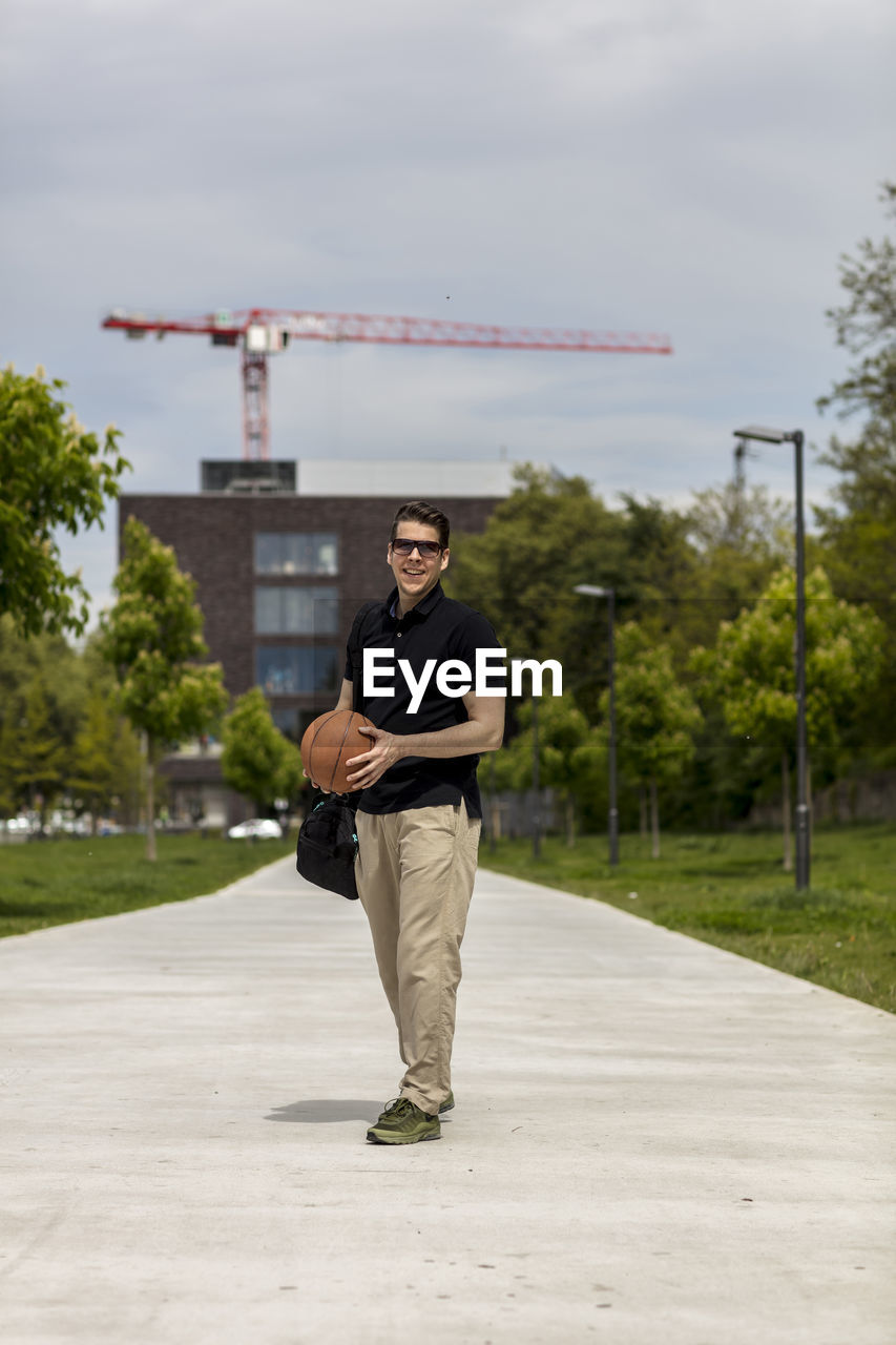 Close-up of mature man throwing basketball while standing outdoors