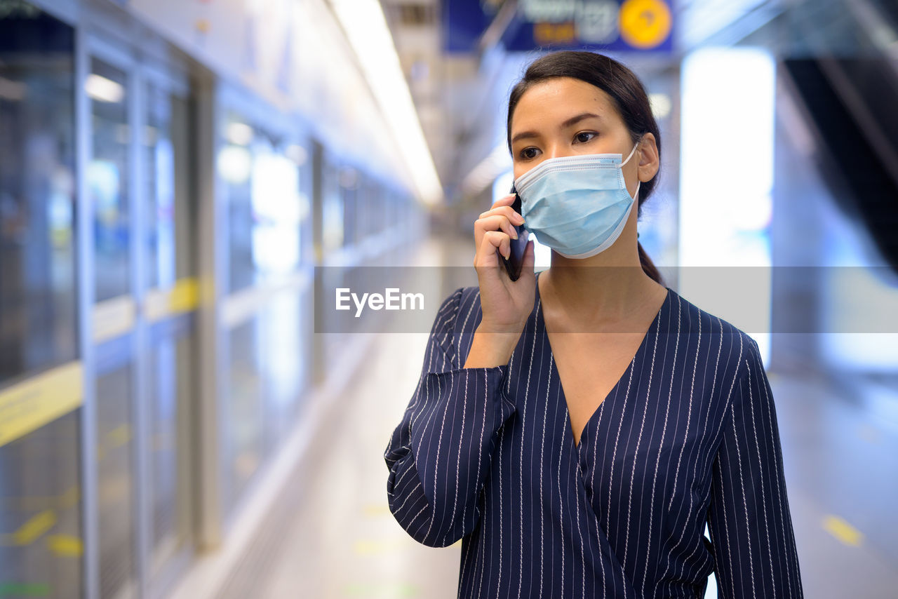 PORTRAIT OF YOUNG WOMAN STANDING ON TRAIN