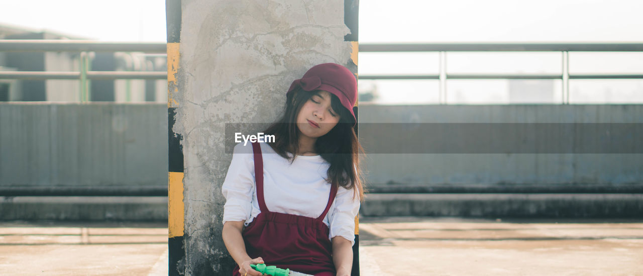 PORTRAIT OF YOUNG WOMAN STANDING OUTDOORS