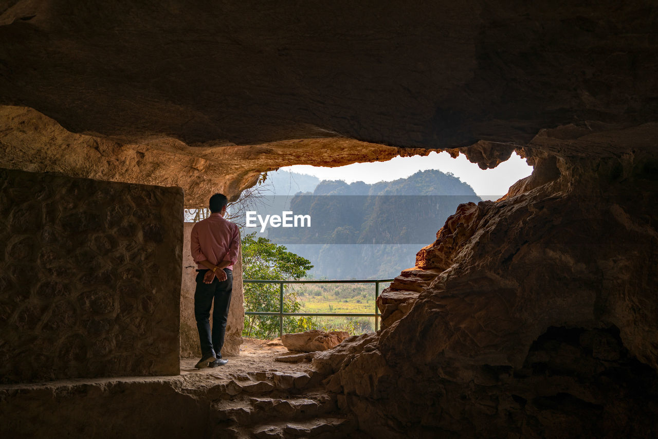 Rear view of man standing in cave