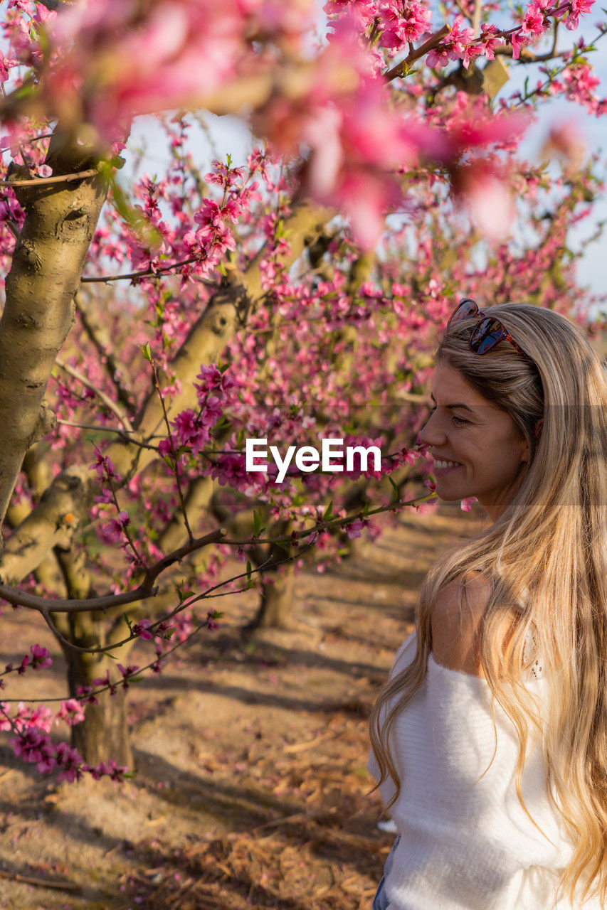 portrait of young woman standing by tree in forest