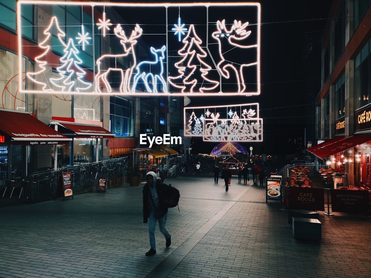 PEOPLE WALKING ON ILLUMINATED STREET AT NIGHT IN CITY