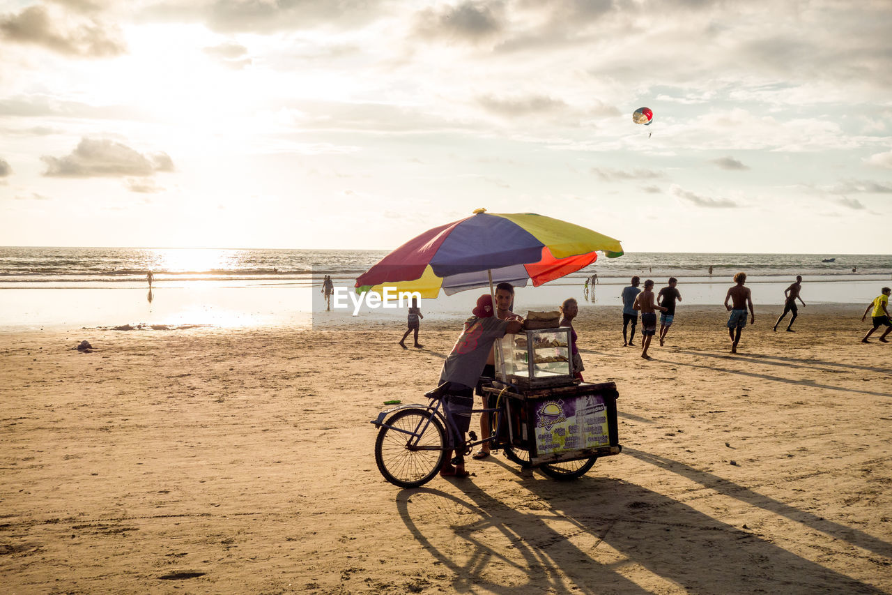 PEOPLE ON BEACH AGAINST SEA