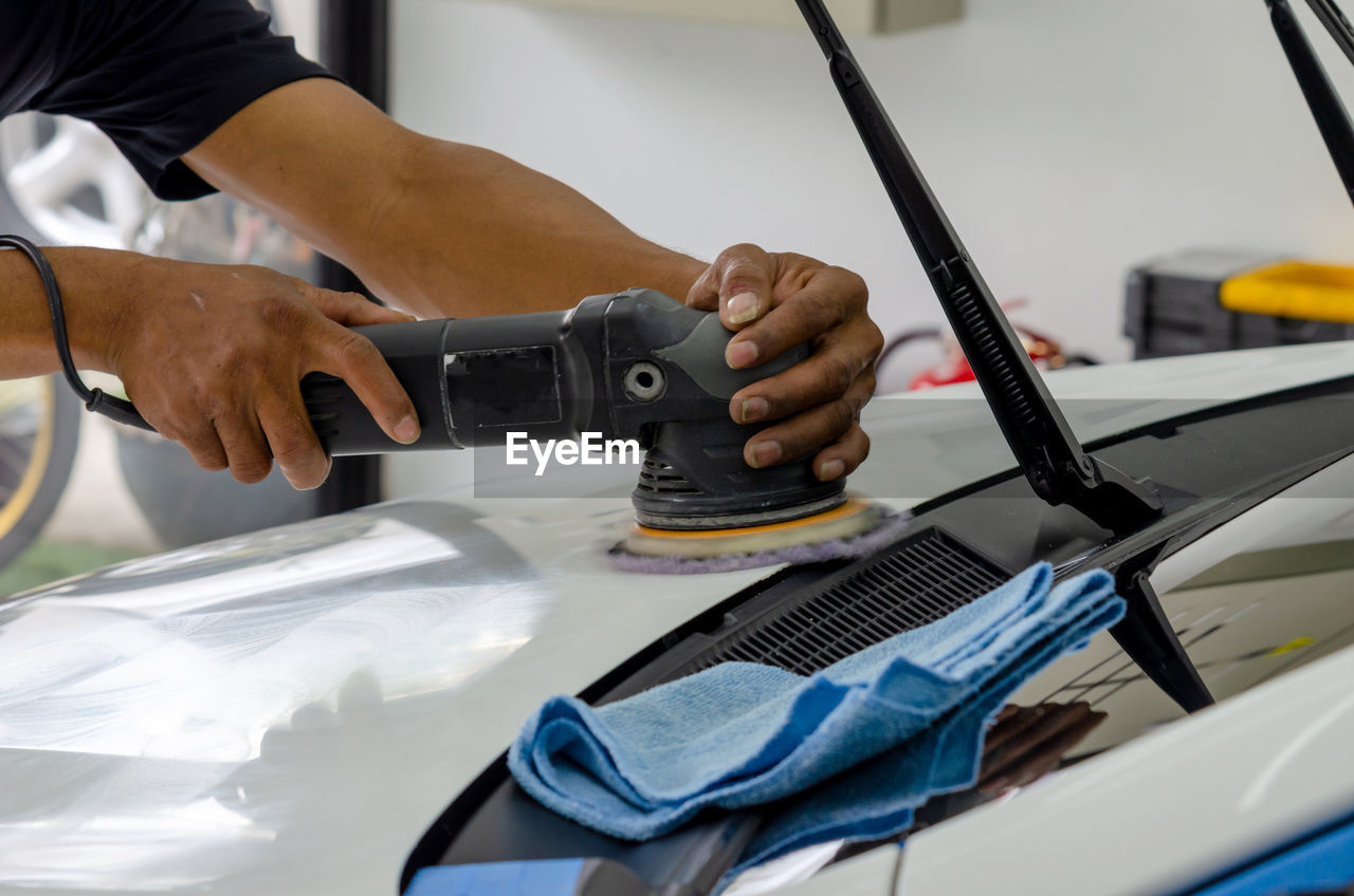 High angle view of man working with equipment on car in garage