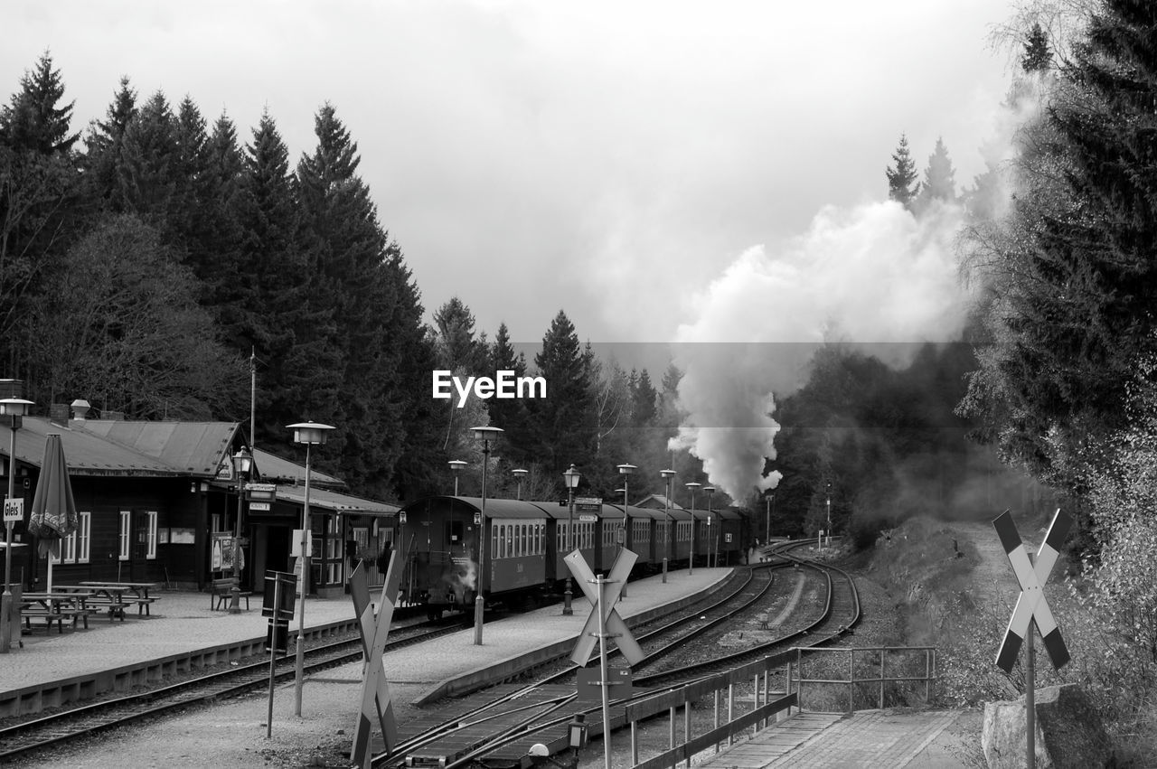 Steam train at railroad station against sky