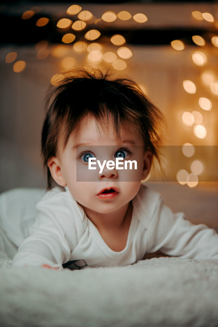 Portrait of cute baby girl on bed at home