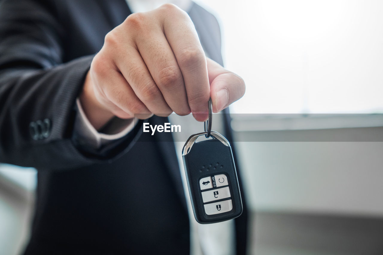 Midsection of insurance agent holding car key 