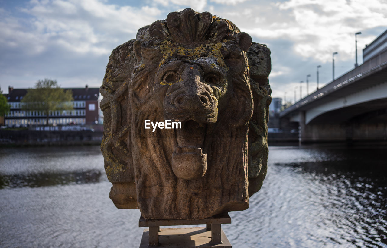 Statue of bridge over river against sky