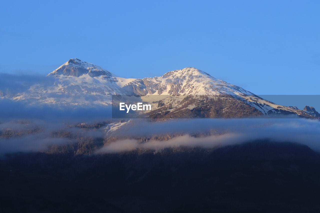 Scenic view of snowcapped mountains against clear blue sky