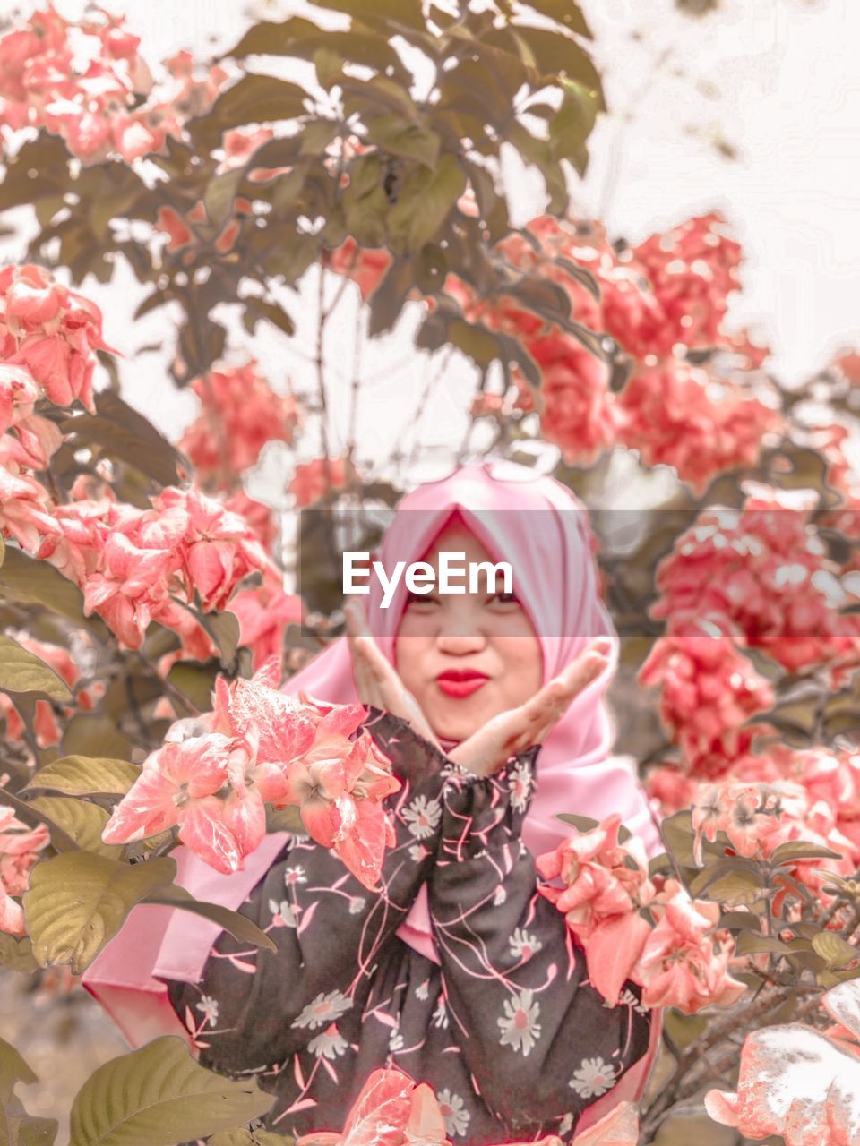 Portrait of woman with pink flowers on tree