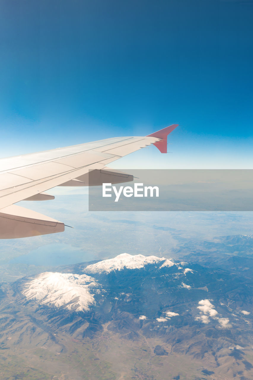 Aerial view of aircraft wing against blue sky