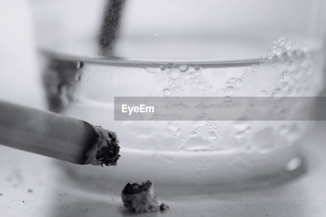 CLOSE-UP OF HAND HOLDING CIGARETTE IN CUP