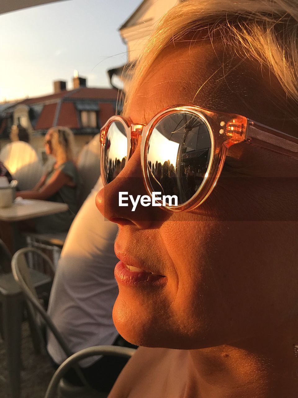 Close-up of woman wearing sunglasses at outdoor cafe during sunset