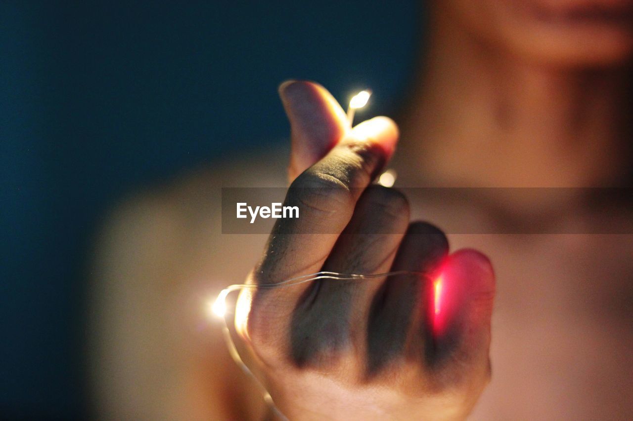 Close-up of hand holding illuminated candle