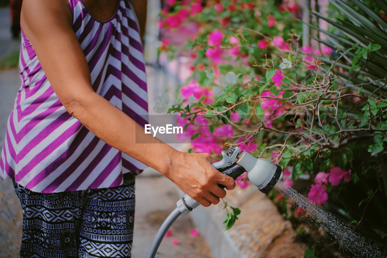 Midsection of woman watering plants