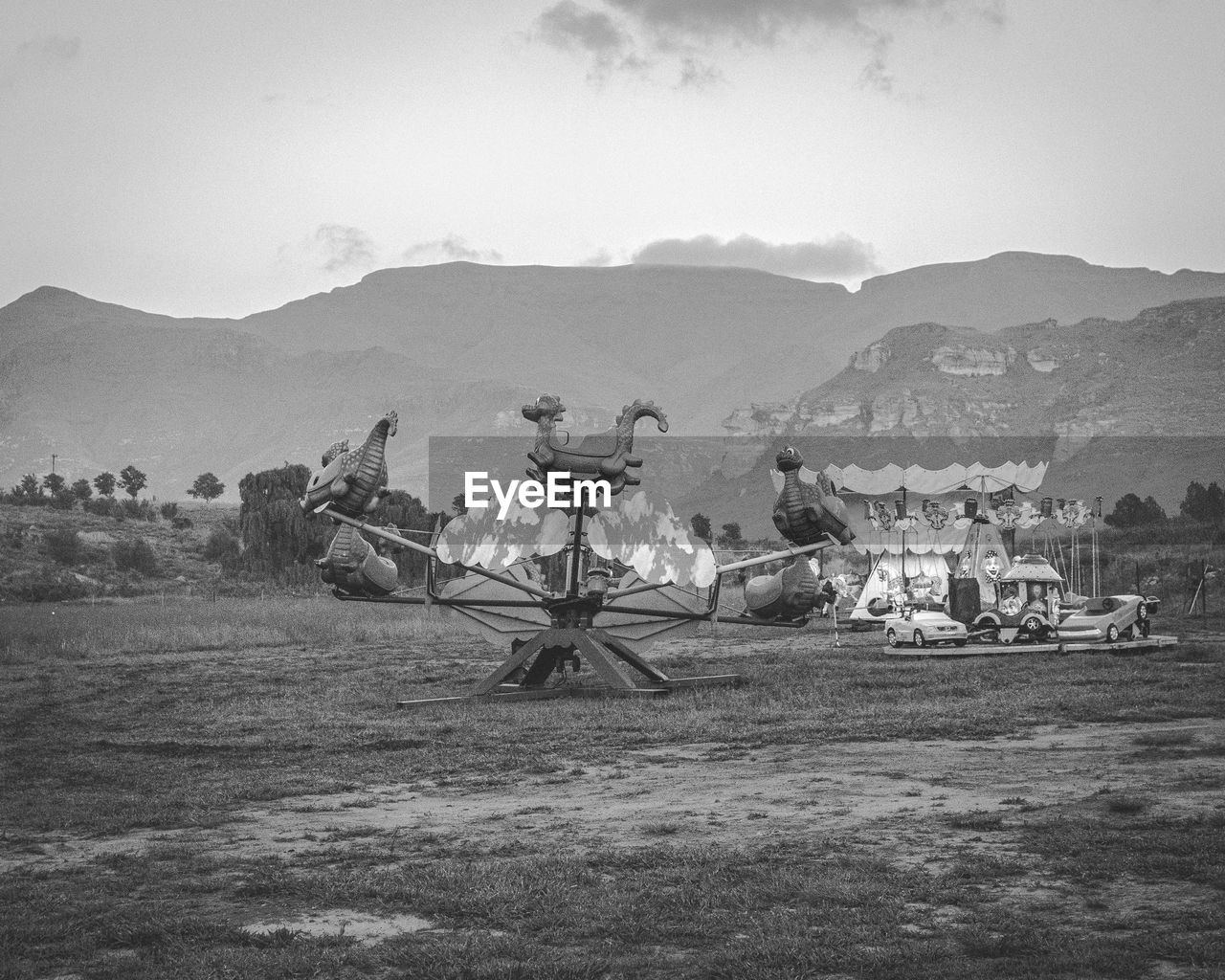 Scenic view of field against sky with roller-coaster 