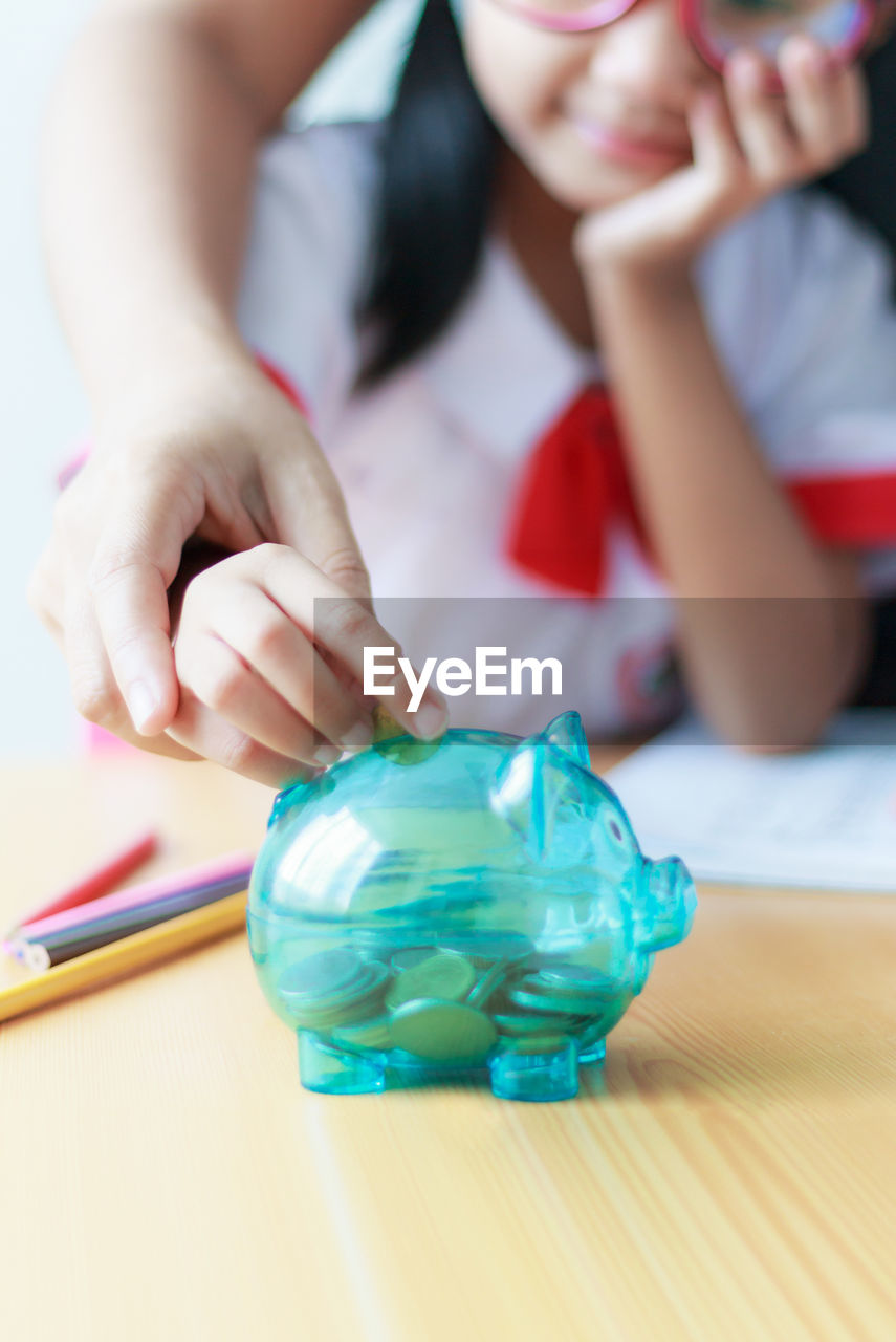 Hands putting coin in piggy bank