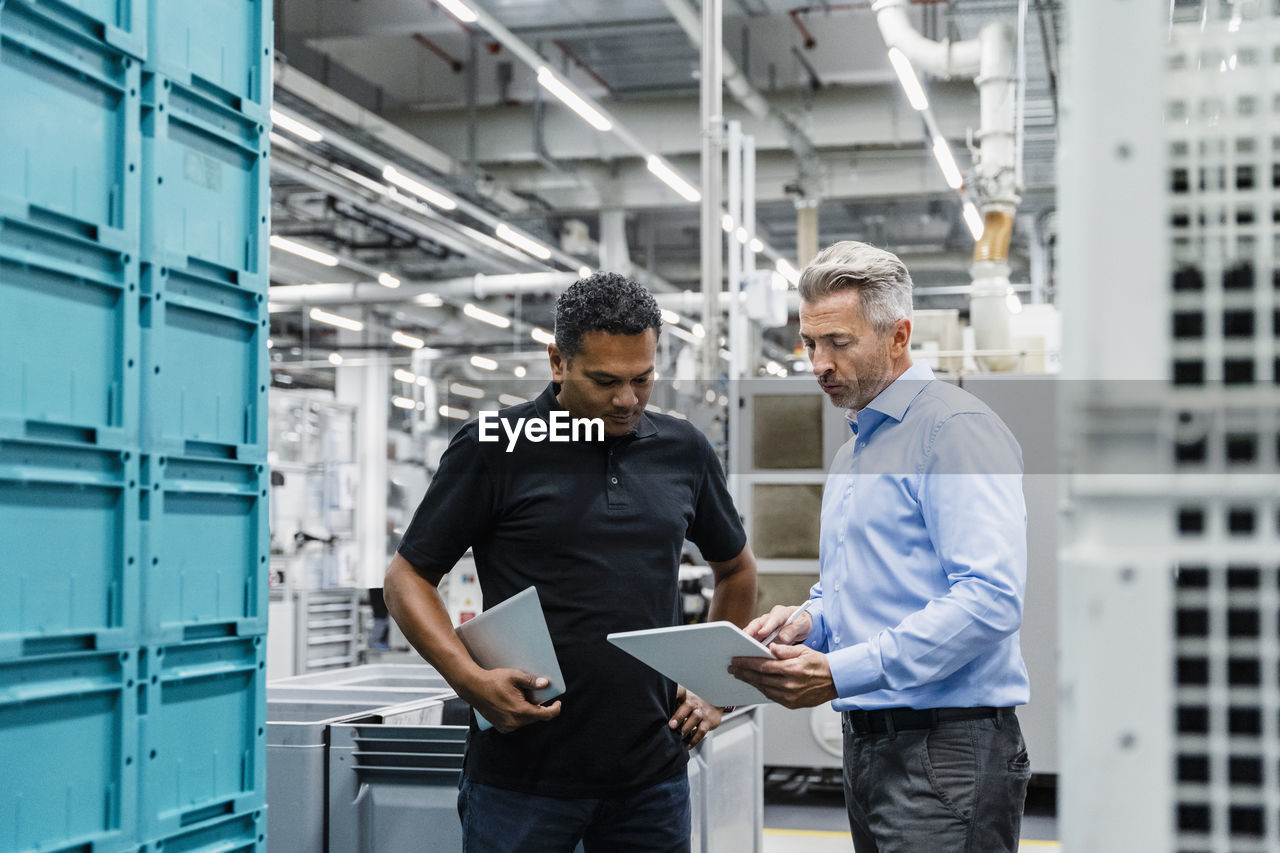 Businessman explaining coworker over tablet pc at warehouse