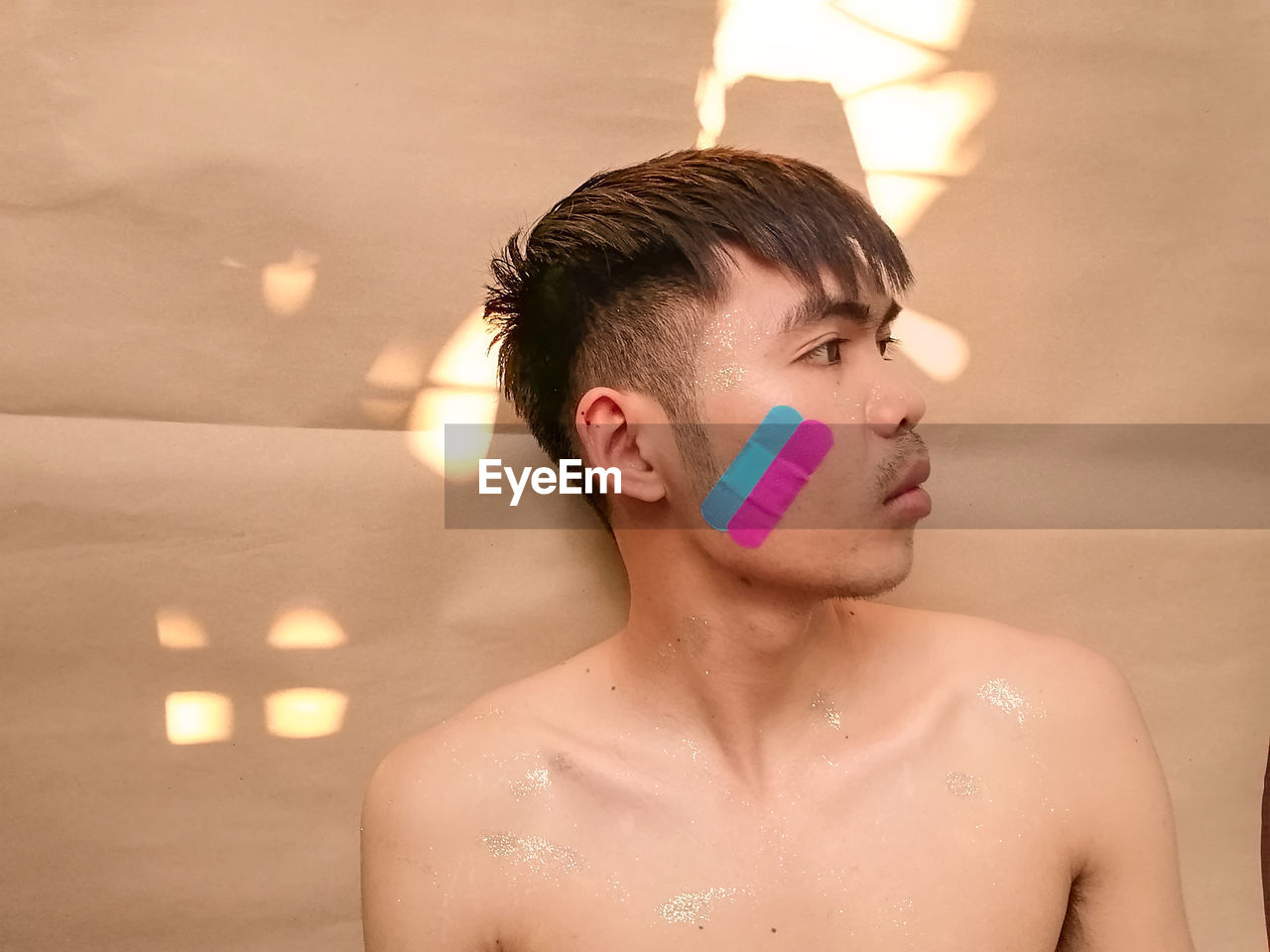 Portrait of young man has plaster on his face 