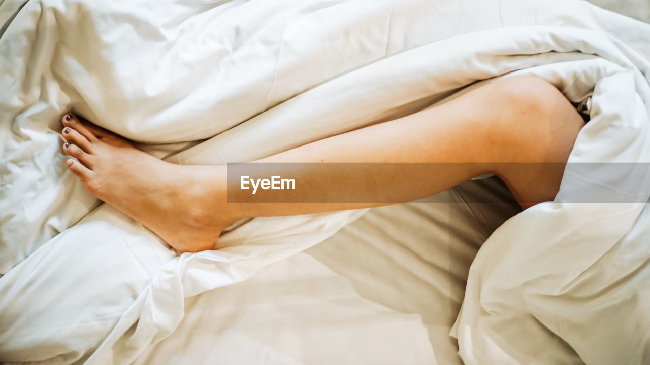 Low section of woman sleeping on bed
