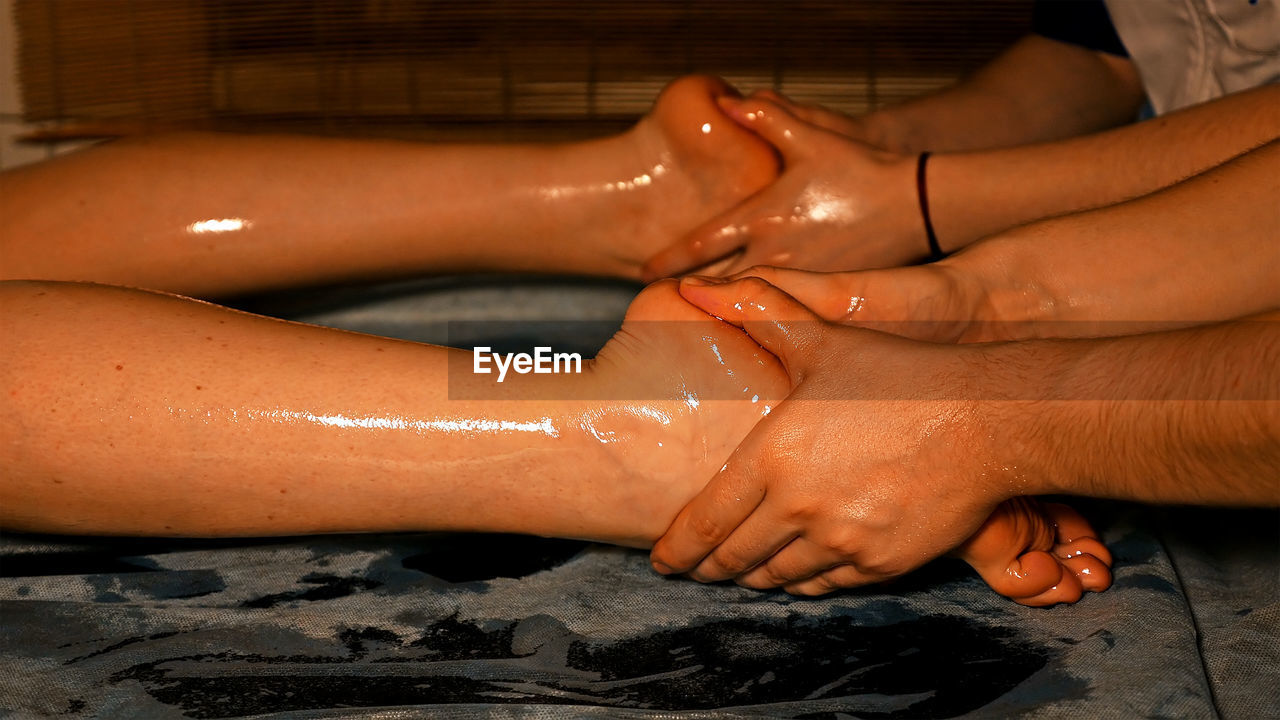 Cropped hands of male masseurs massaging female customer at beauty spa