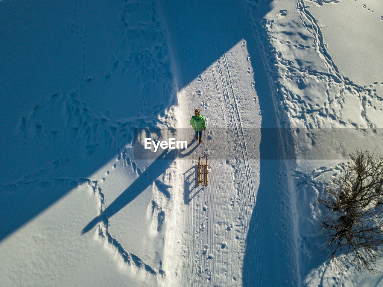 High angle view of woman pulling sleigh while walking on snow covered land