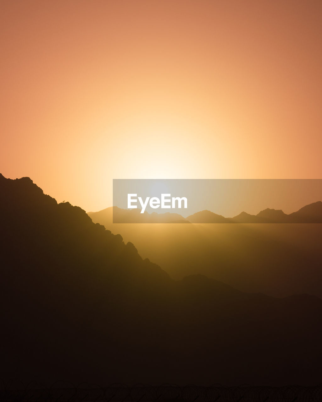 Scenic view of silhouette mountains against orange sky