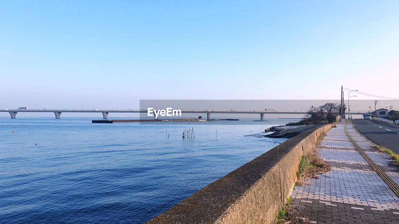 Bridge over calm sea against clear sky