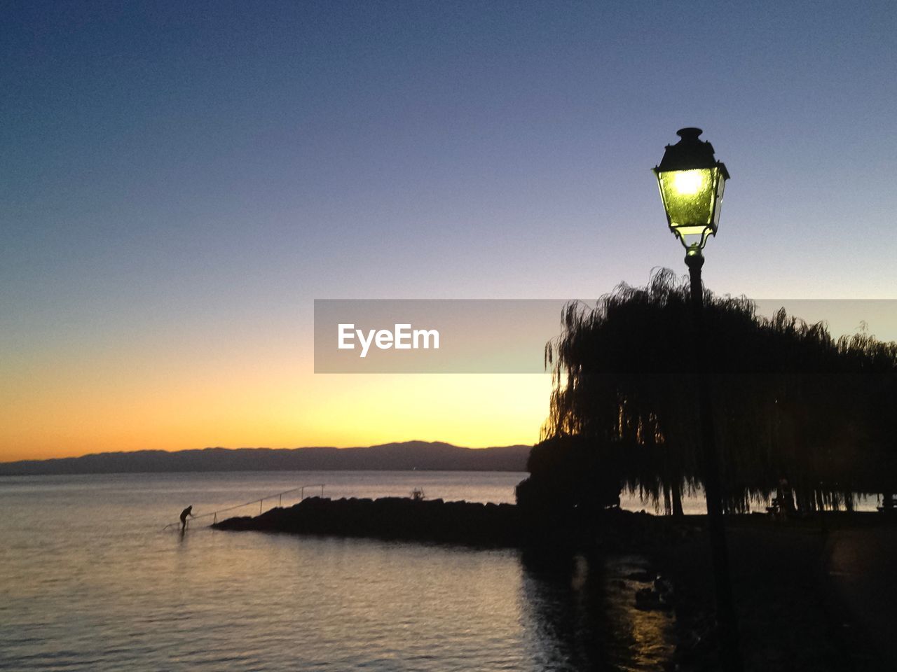 Scenic view of lake against clear sky during sunset