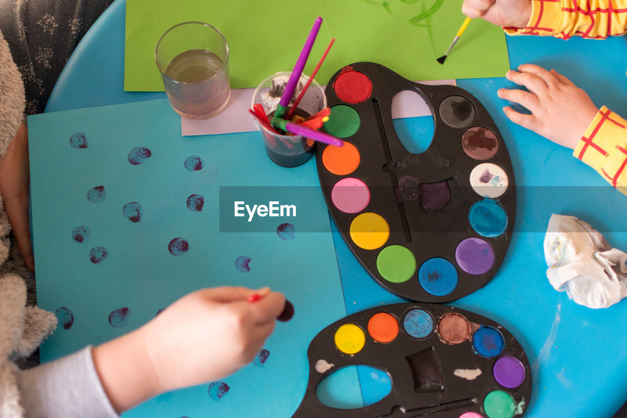 High angle view of hands on multi colored table painting