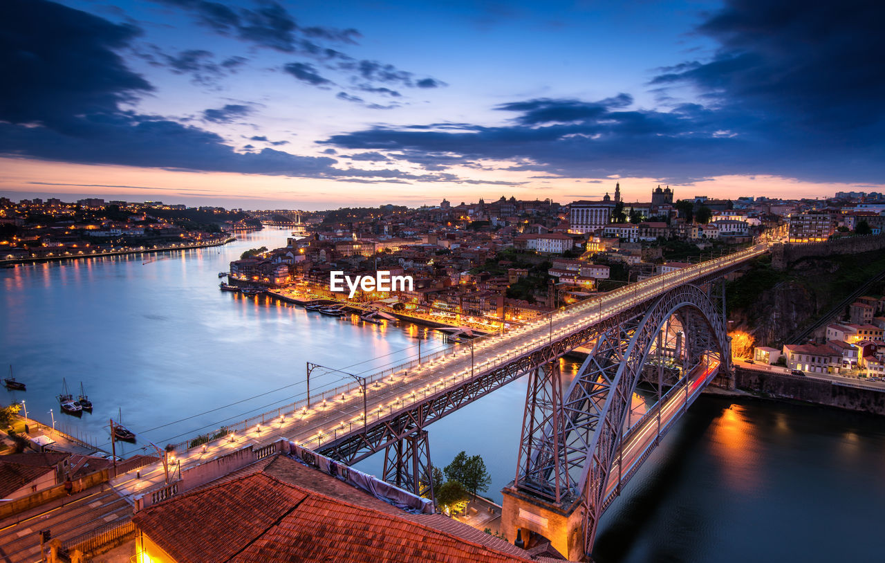 High angle view of illuminated bridge over river by buildings against sky