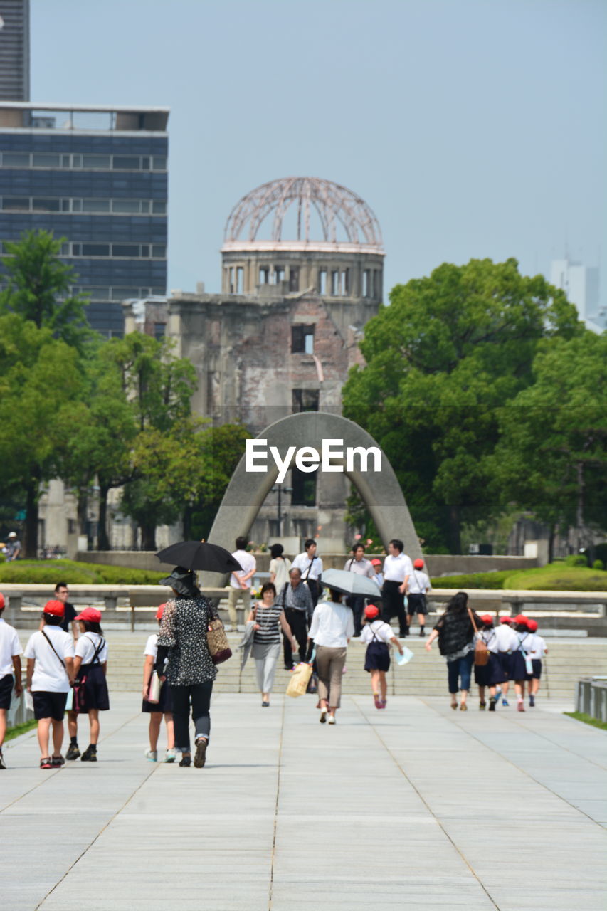 People walking in park against clear sky