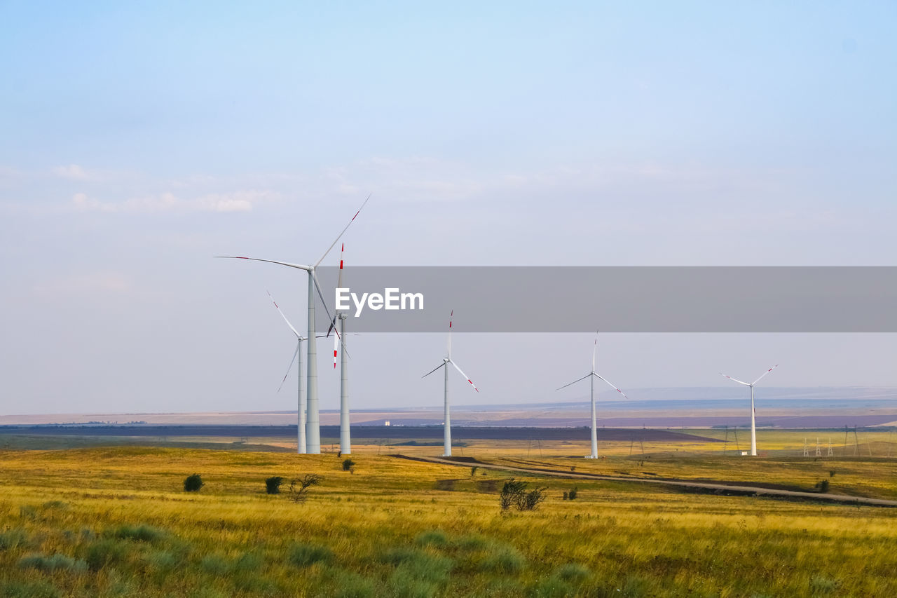 WIND TURBINES ON LAND AGAINST SKY