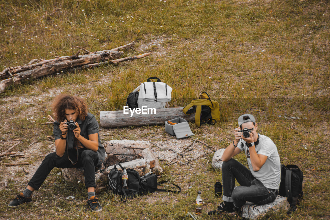 FULL LENGTH OF YOUNG COUPLE SITTING ON LAND IN FOREST