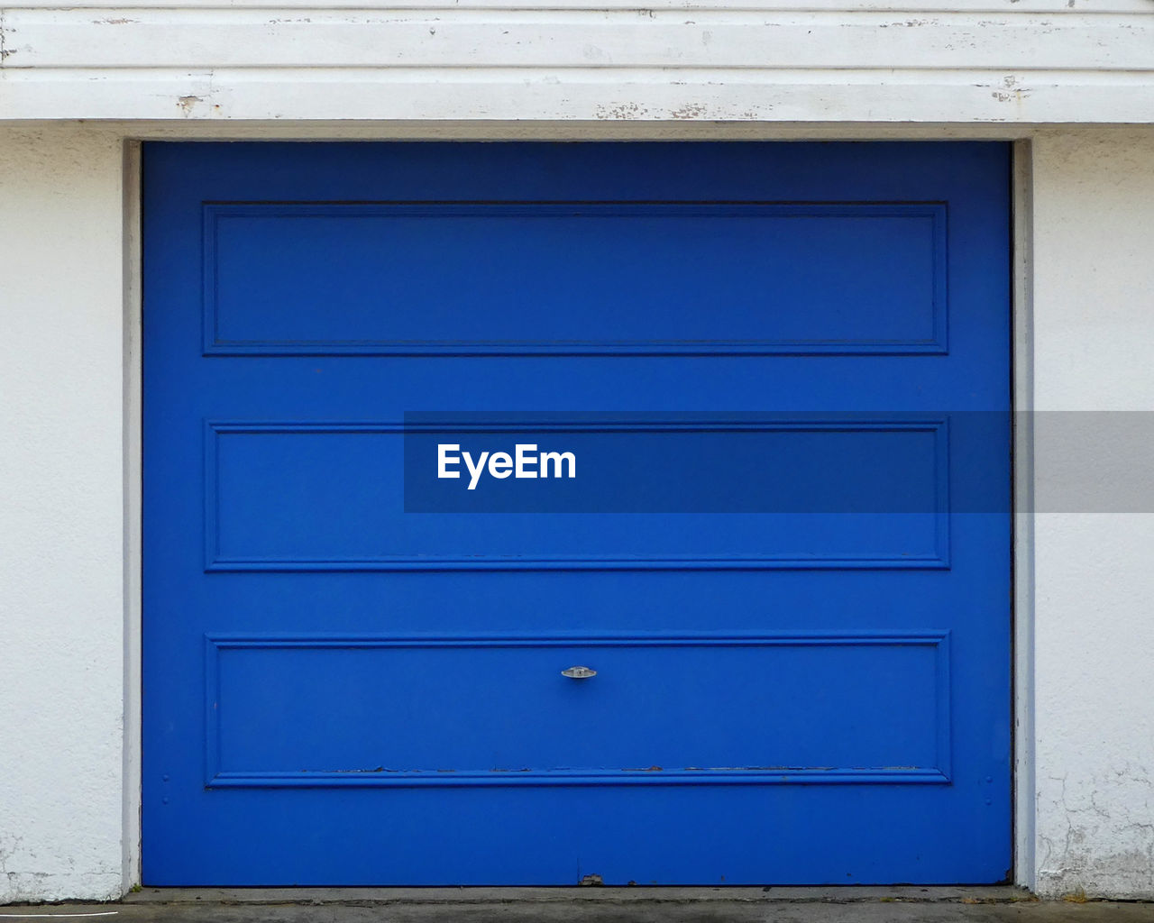 Garage door,cobalt blue on white cement rendered wall