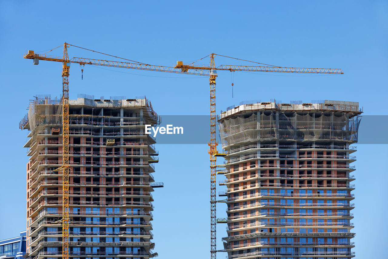 Modern construction of multi-storey twin towers of residential buildings with help of tower cranes