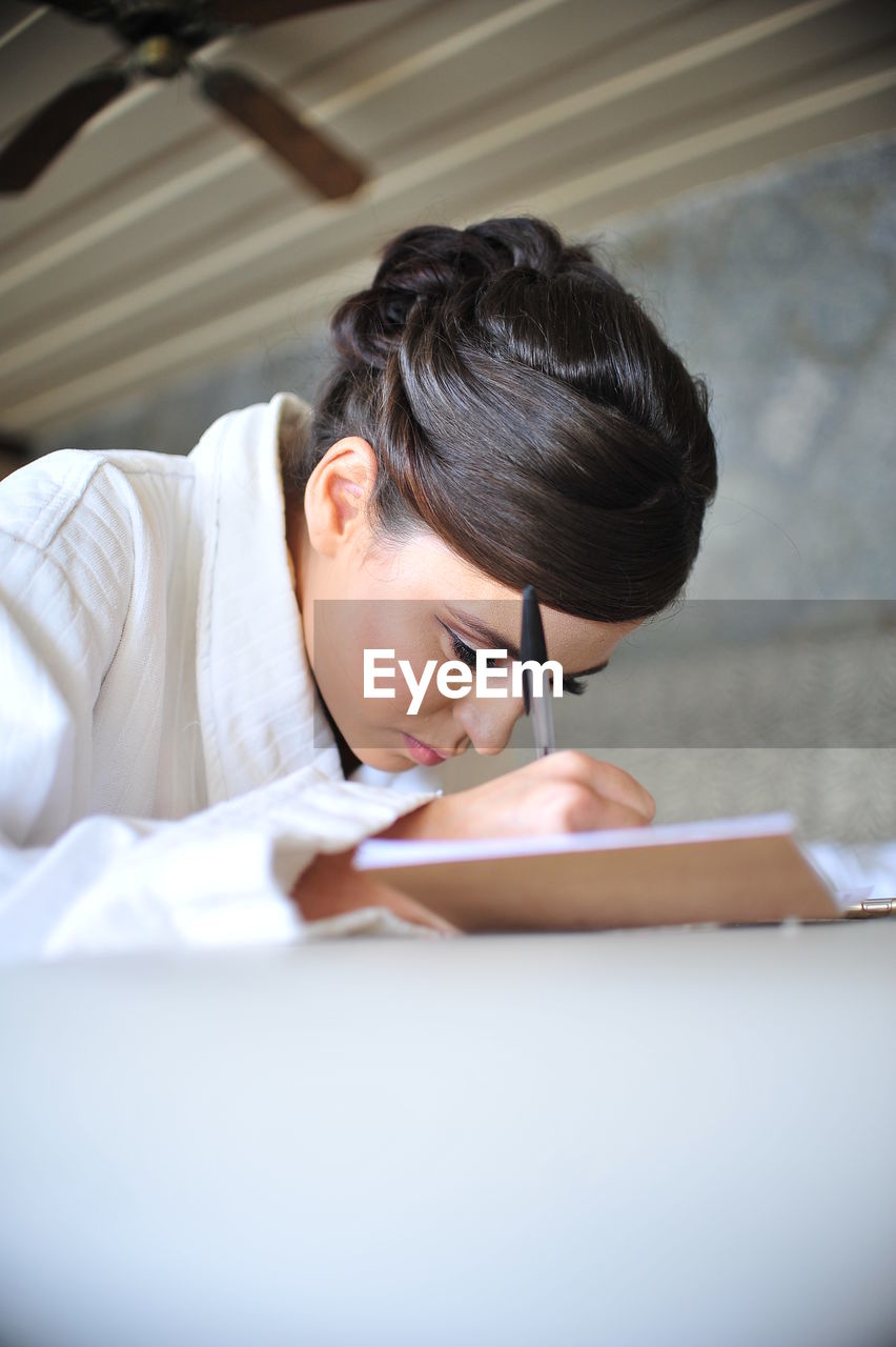 Woman writing in book on table